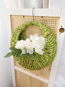 Detailed view of woven corn rope basket with white silk flowers for wall decor