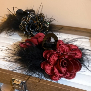 Close-up of luxury flower hair claws with silk petals and delicate feathers in a vintage box