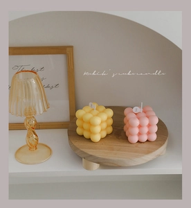 Detailed view of handmade pink and yellow Rubik's cube bubble candles on a wooden tray