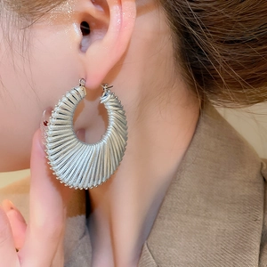 Gros plan de boucles d'oreilles créoles tressées argentées portées par un mannequin