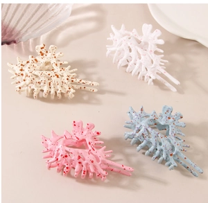 Detailed view of four coral-shaped hair claws in assorted colors on neutral background