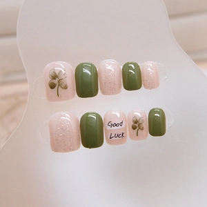Short square press-on nails in avocado green and pink with glitter and clover pattern