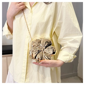 Close-up of golden flower shaped clutch bag with metallic mirror finish and chain strap
