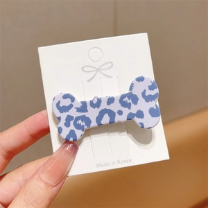 Close-up of blue leopard print bone-shaped hair clip on a white display card detail