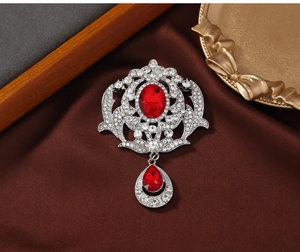 Macro detail of vintage baroque brooch with red rubies and white crystals on silk