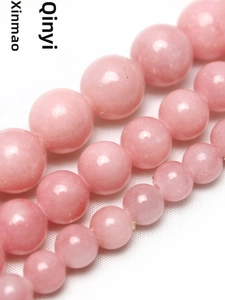 Gros plan de perles rondes en jade rose poli avec texture de pierre naturelle pour bijoux