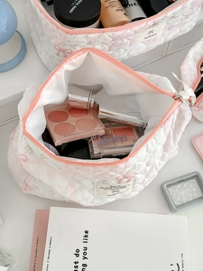 Close-up of quilted floral makeup bag with pink flower patterns and spacious zipper opening