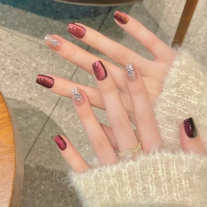 Deep red cat eye press-on nails with sparkling snowflake rhinestones for winter style