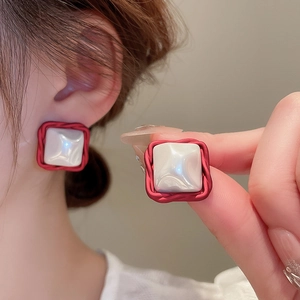 Macro shot of red square earrings with twisted rope borders and white pearlescent inlay