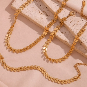 Detailed close-up of 18K gold plated leaf chain necklace with lobster clasp on silk