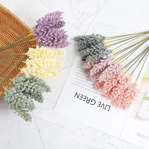Flat lay of artificial wheat ear bouquets in five colors on white marble background