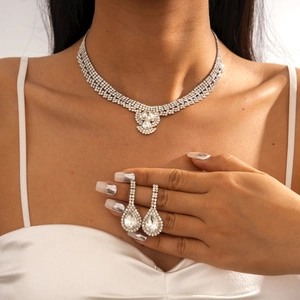 Détail du collier et des boucles d'oreilles goutte argentés portés par un mannequin