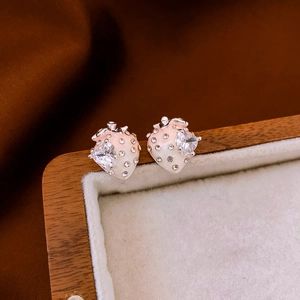 Vue macro de boucles d'oreilles fraise plaquées or avec émail rose et zircon cœur