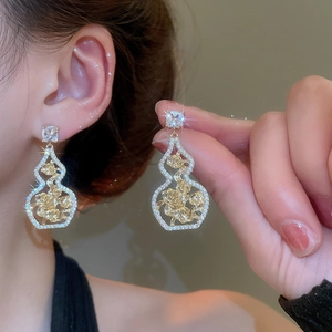 Macro shot of gold gourd earrings with rose engraving and shimmering zircon detail