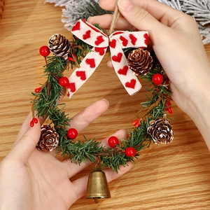 Christmas wreath with green pine needles, red berries, cones and a small metal bell