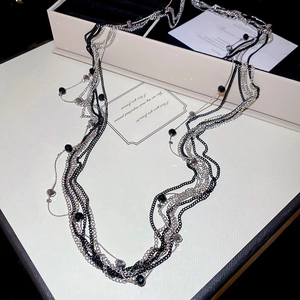 Detailed view of multilayer long necklace with black glass beads and silver chain