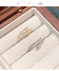 Macro shot of silver and gold snake rings with cubic zirconia inlay on a wooden box