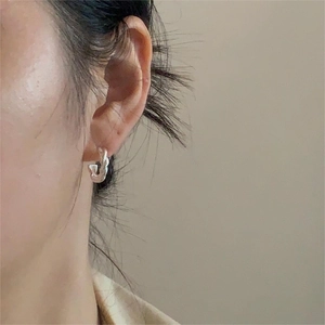 Elegant 925 sterling silver twisted hoop earrings worn by a model in a minimalist style