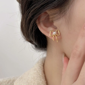 Elegant 925 sterling silver gold bow stud earrings with white pearl detail on model