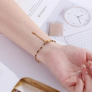 Close-up of golden enamel bracelet with dark beads on woman wrist with trendy lifestyle props