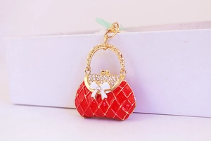 Macro detail of red quilted handbag keychain with white bow and sparkling rhinestones