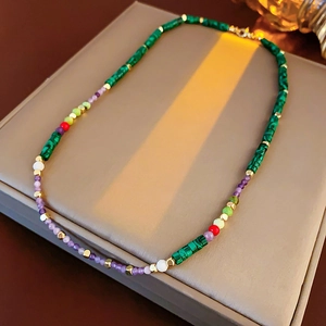 Macro detail of retro beaded necklace with malachite and gold beads on jewelry box