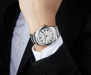 Close-up of a silver stainless steel watch with Roman numerals on a wrist in a suit