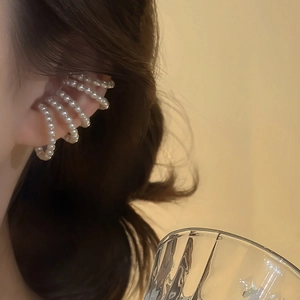 Close-up of a French vintage multilayer pearl ear cuff worn by a model in warm light