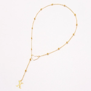 Detailed shot of golden ball chain necklace with heart link and letter X pendant