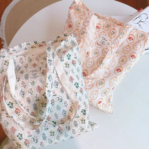 Floral print cotton canvas tote bags for women on a white table with books