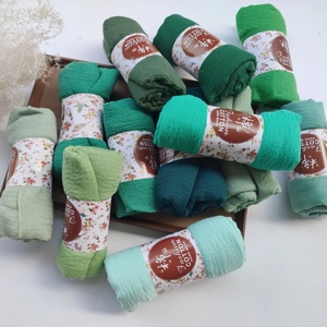 Detailed close-up of wrinkled cotton scarves with pleated texture and paper labels