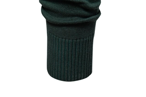 Detail of dark green knit sweater featuring classic ribbed cuffs and dense fabric texture