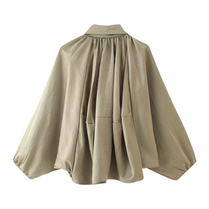 Detail of glossy champagne satin bomber jacket with batwing sleeves and gathered hem
