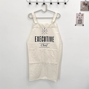 Detail of beige cotton linen apron featuring executive chef print and front pocket