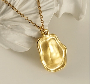 Macro shot of gold irregular lava pendant necklace on white minimalist art stone