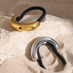 Detail of gold and silver moon-shaped stainless steel charms on black elastic hair ties