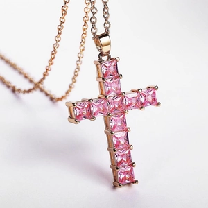 Macro shot of rose gold cross pendant with square-cut pink zircon stones and shiny metal chain