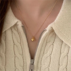 Elegant gold heart and key necklace pendant on a minimalist thin chain worn by model