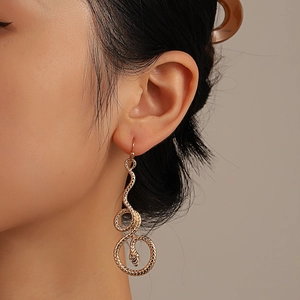 Vintage gold snake-shaped dangle earring with detailed scale texture on a model