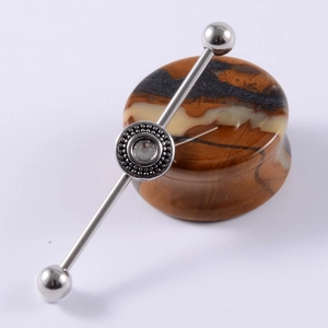 Macro view of stainless steel industrial barbell featuring a sparkling clear gemstone inlay