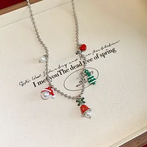 Close-up of Christmas necklace with red heart, tree, and bell pendants on silver chain