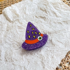 Macro detail of purple glitter witch hat hair claw with crescent moon patterns