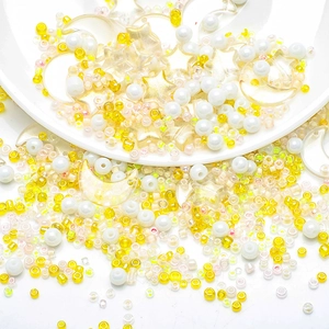 Detail of yellow seed beads with frosted star and moon charms for DIY jewelry making