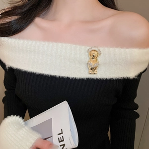 Close-up of a sparkling gold bear brooch with white crystals pinned to a knit sweater