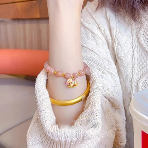 Detail of beaded sunstone bracelet with gold rocking horse charm and matte gold bangle