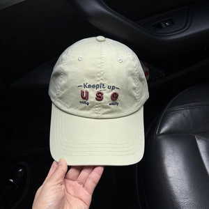 Detail of embroidered letters on soft cotton beige baseball cap with curved brim