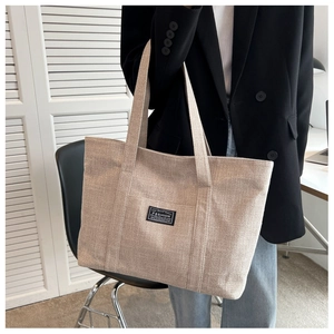 Close-up of beige canvas tote bag on model showing large capacity and fashion label
