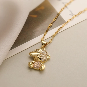 Détail d'un pendentif ours avec casquette et pierre rose sur un collier doré