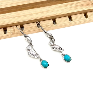 Detail of vintage silver feather earrings with oval blue stone in bohemian style