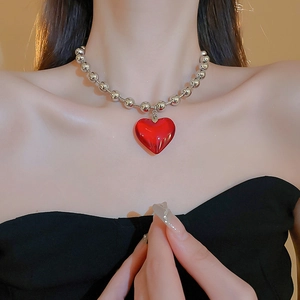 Close-up of stylish silver beaded necklace featuring a glossy red resin heart pendant